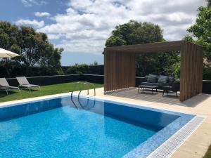 a swimming pool with a wooden pergola next to a house at Quinta de Santa Clara in Ponta Delgada