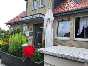 a white umbrella sitting in front of a building at Hotel & Restaurant Blume in Wolfsburg