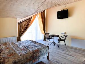 um quarto com uma cama, uma mesa e uma televisão em Апартаменти "Золота Баня" em Skhidnitsa