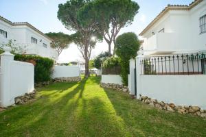 ein Hof eines weißen Hauses mit einem Zaun in der Unterkunft LA BARROSA-NOVO SANCTI PETRI, wifi, aire acondicionado, parking in Chiclana de la Frontera