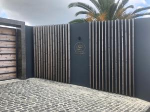 a fence with a gate with a palm tree behind it at Quinta de Santa Clara in Ponta Delgada