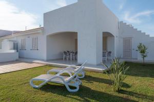 a white house with two lounge chairs in the yard at Blue Sea Villas by Wonderful Italy in Ostuni