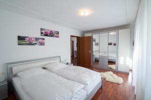 1 dormitorio con cama blanca y espejo en Ferienwohnung Michiko - Albstadt, en Albstadt