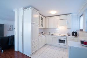 cocina con armarios blancos y suelo de baldosa blanca en Ferienwohnung Michiko - Albstadt, en Albstadt