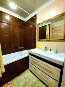 uma casa de banho com um lavatório, uma banheira e um espelho. em Apartment Ushakova 16 em Dnipro
