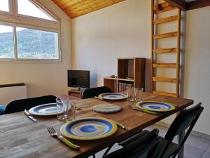 - une table en bois avec des assiettes et des ustensiles dans l'établissement Agréable T3 mezzanine jusqu'à 5 personnes, à Briançon