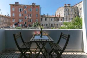 a table and two chairs on a balcony with a window at La Preziosa Rooms in Pula