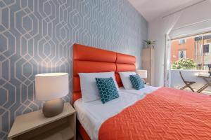 a bedroom with a bed with an orange headboard at La Preziosa Rooms in Pula