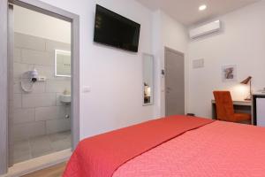 a bedroom with a red bed and a bathroom at La Preziosa Rooms in Pula
