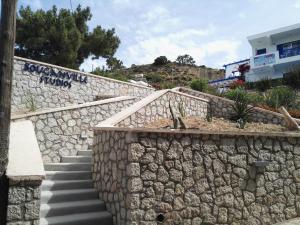 a stone wall with stairs next to a building at Bouganville Studios Stegna in Archangelos