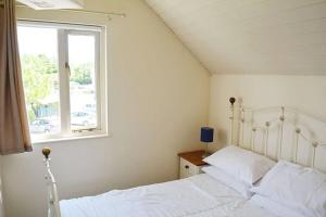 a bedroom with a white bed and a window at Shelduck Lodge in South Cerney