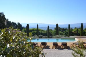 uma piscina com cadeiras e vista para as montanhas em Le Jas de Joucas Hôtel-Restaurant em Joucas