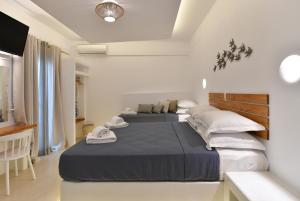 2 letti in una camera bianca con televisore di Ammos Luxury Rooms & Home a Naoussa