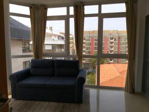 a blue couch sitting in front of a large window at Apartamento en Ribeira(centro) 4* planta in Ribeira