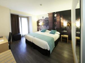 um quarto de hotel com uma cama grande com almofadas azuis em ELE Enara Boutique Hotel em Valladolid