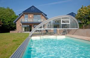 a house with a swimming pool in front of a house at Villa La Cigale in Boltenhagen