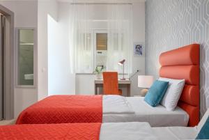 a bedroom with an orange and white bed and a desk at La Preziosa Rooms in Pula