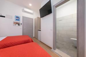 a bedroom with a red bed and a bathroom at La Preziosa Rooms in Pula