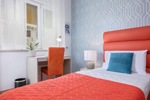 a bedroom with a red bed with a blue pillow and a desk at La Preziosa Rooms in Pula