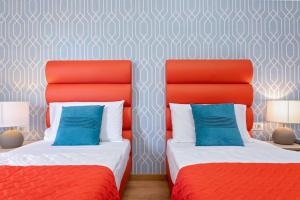 two beds in a room with red and blue at La Preziosa Rooms in Pula