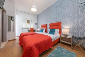 a bedroom with two beds with red sheets and blue pillows at La Preziosa Rooms in Pula