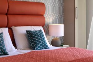 a bedroom with a bed with a red headboard and a lamp at La Preziosa Rooms in Pula
