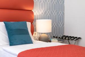 a bedroom with a bed with a red headboard and a lamp at La Preziosa Rooms in Pula