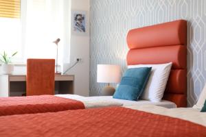 a bedroom with two beds and a red headboard at La Preziosa Rooms in Pula
