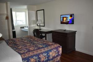 a bedroom with a bed and a desk and a television at Valley Hotel in Rosemead