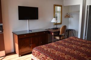 a hotel room with a bed and a desk with a television at Valley Hotel in Rosemead