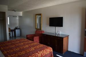 a hotel room with a bed and a chair and a television at Valley Hotel in Rosemead