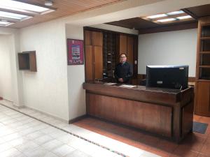 a man standing at a reception desk in a lobby at Apartamentos Percales in Bogotá