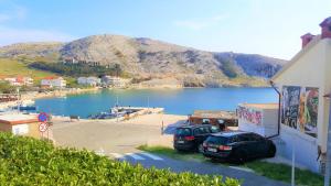 two cars parked in a parking lot next to a body of water at Apartments Niko Metajna, island Pag in Metajna