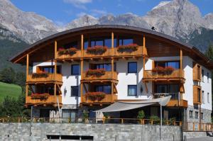 un edificio con balcones y flores frente a las montañas en Sunnsait - Appartements für Genießer, en Maria Alm am Steinernen Meer