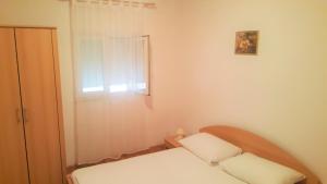 a small room with two beds and a window at Apartments Niko Metajna, island Pag in Metajna