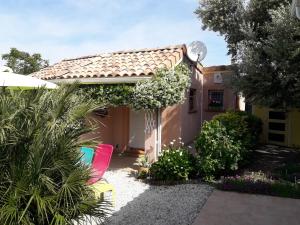 einen Garten mit einem Haus und einigen Stühlen in der Unterkunft Les Cyprès Florentins in Colomiers