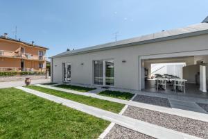 a white house with a patio and grass at Garda Guest House in Colà di Lazise