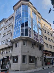 a tall building with glass windows on a street at Apartamento en Ribeira(centro) 4* planta in Ribeira
