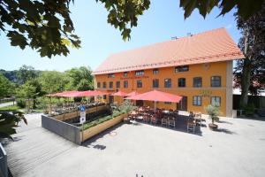 um edifício com mesas, cadeiras e guarda-sóis vermelhos em Hotel Kunstmühle em Mindelheim