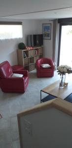 una sala de estar con 2 sillas rojas y una mesa. en Gite de kernaet avec piscine, en Plougonvelin