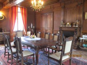una sala da pranzo con tavolo, sedie e lampadario pendente di Le domaine de Beaufai a Beaufai