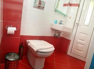 a red and white bathroom with a toilet and a sink at Christopoulos Villas in Aigio