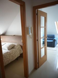 - une chambre avec une porte menant à un lit et un canapé bleu dans l'établissement ÁTICO EN RIBEIRA(centro), à Ribeira