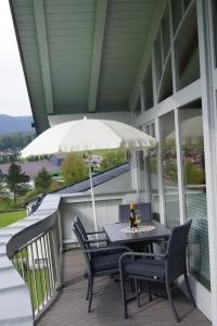 un tavolo e sedie su un portico con ombrellone di Apart Konrad a Ehrwald