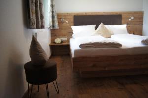 una camera da letto con un letto con lenzuola bianche e una sedia di Apart Konrad a Ehrwald