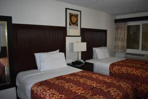 a hotel room with two beds and a lamp at Valley Hotel in Rosemead