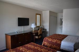 a hotel room with two beds and a desk with a television at Valley Hotel in Rosemead