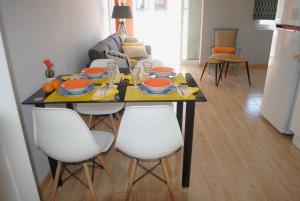 a dining room table with white chairs and orange dishes on it at Aparatamento Barraques Gandia Playa para 3-4 personas 150 metros de la playa in Gandía