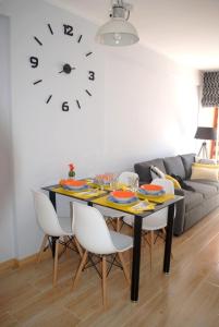 a dining room table with chairs and a clock on the wall at Aparatamento Barraques Gandia Playa para 3-4 personas 150 metros de la playa in Gandía