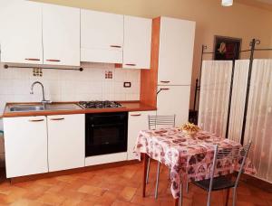 a kitchen with white cabinets and a table and a sink at La Piccola Toscana 2 in Peccioli